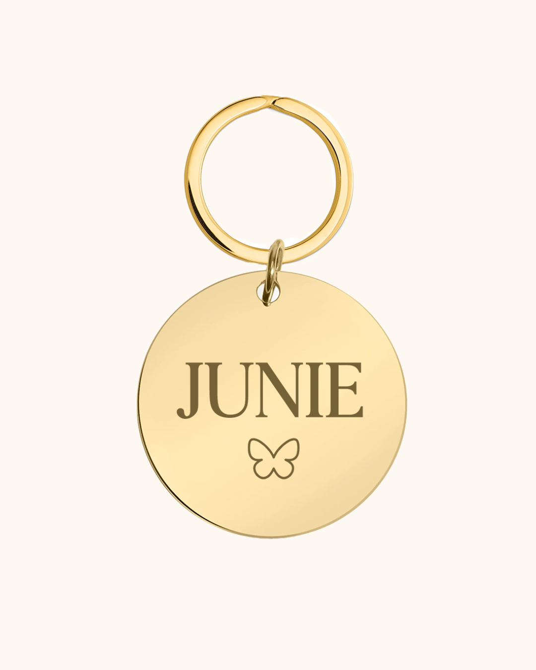 Gold pet tag with 'JUNIE' engraved on a white background