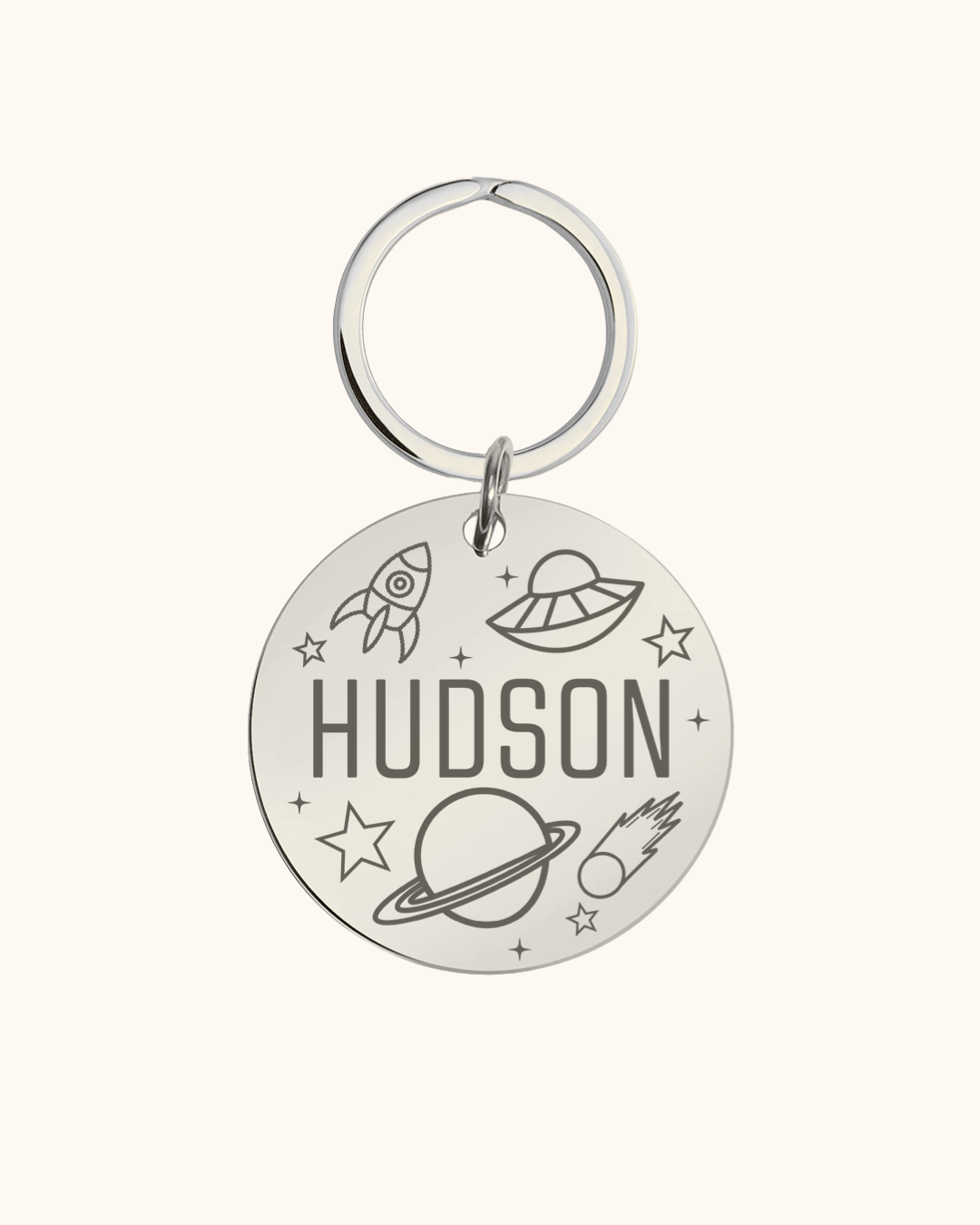 Silver pet tag with 'Hudson' and space-themed designs on a white background