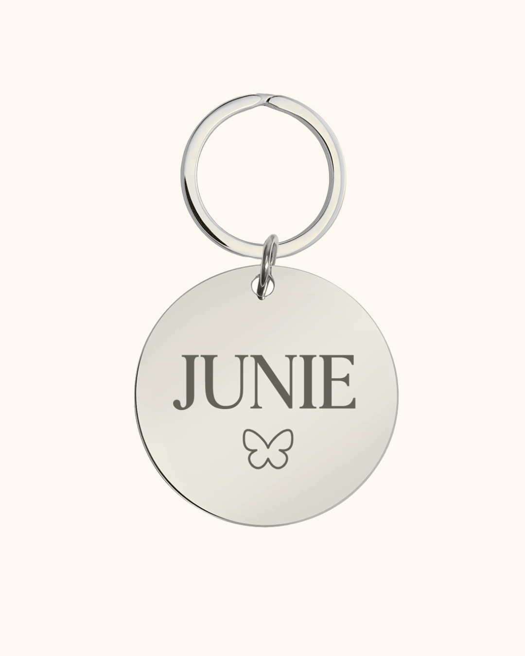 Silver pet tag with 'JUNIE' and a butterfly on a white background